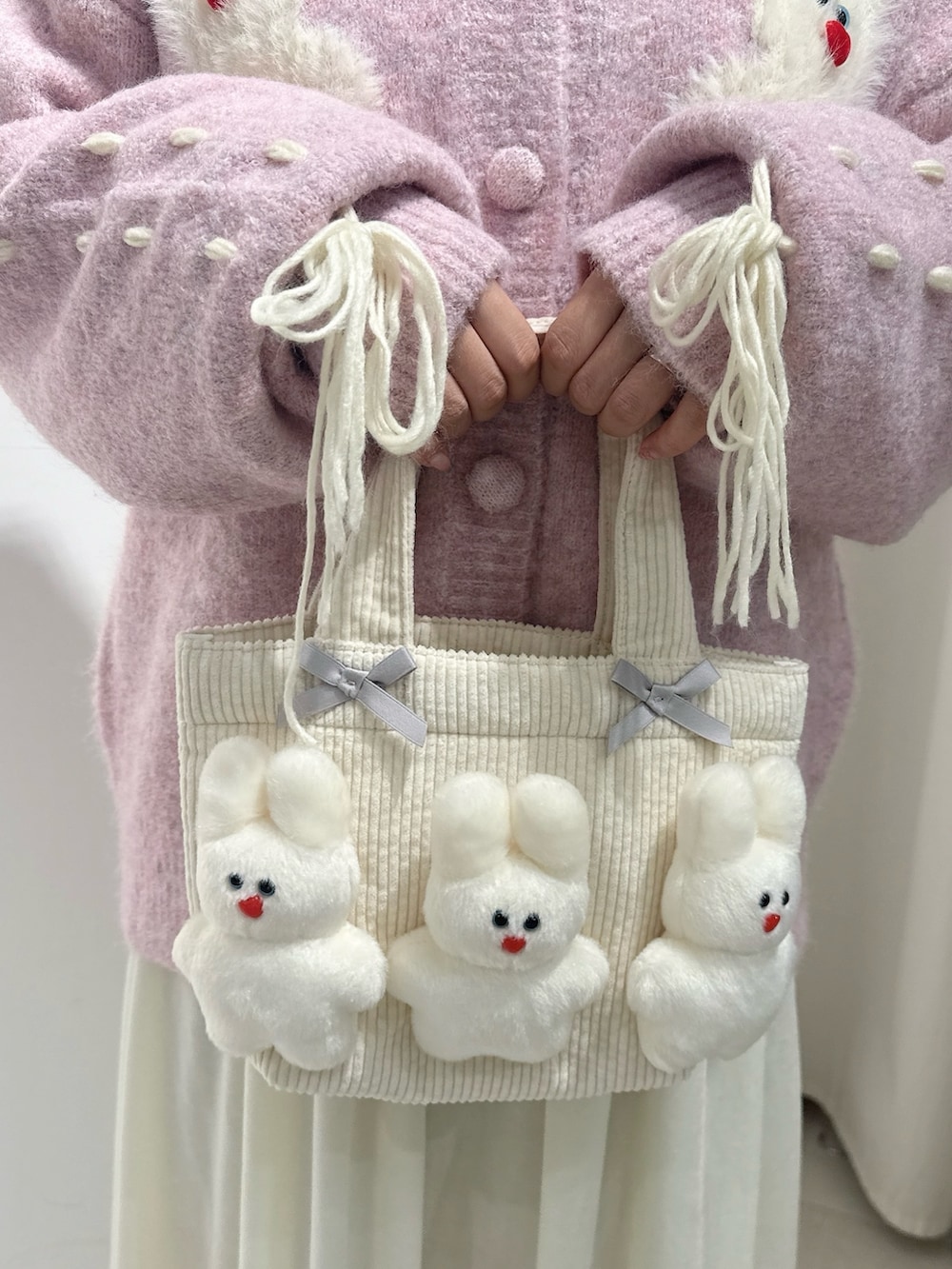 ピンク系のブーツ、ピンク系のカーディガン/ボレロ、ホワイト系のワンピースを着用したレディースの秋コーディネートの6枚目の写真