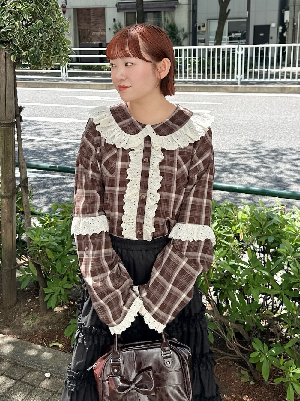ブラウン系のハンドバッグ、ブラウン系のシャツ/ブラウス、ブラック系のスカートを着用したレディースの春コーディネートの3枚目の写真