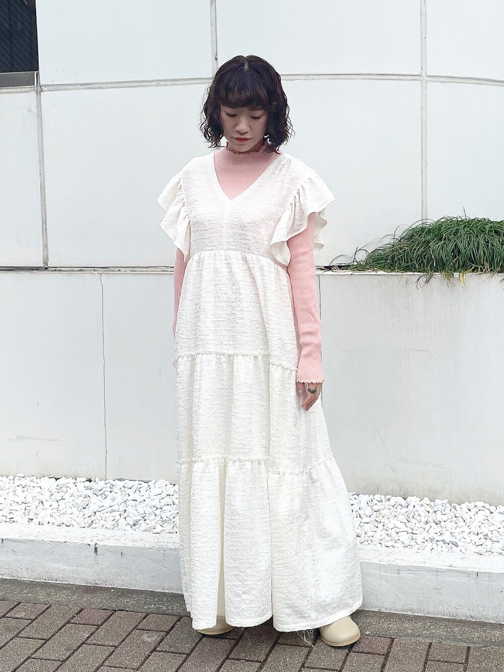 ピンク系のニット/セーター、ホワイト系のワンピース、ベージュ系のブーツを着用したレディースの冬コーディネートの2枚目の写真