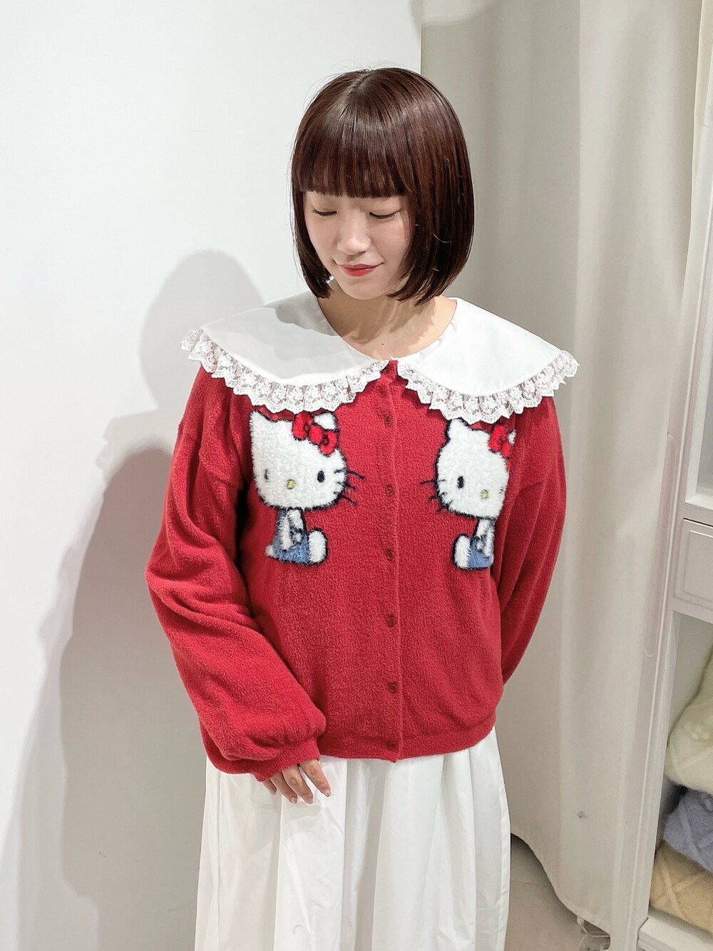 ホワイト系のワンピース、レッド系のカーディガン/ボレロ、ホワイト系のローファーを着用したレディースの秋コーディネートの4枚目の写真