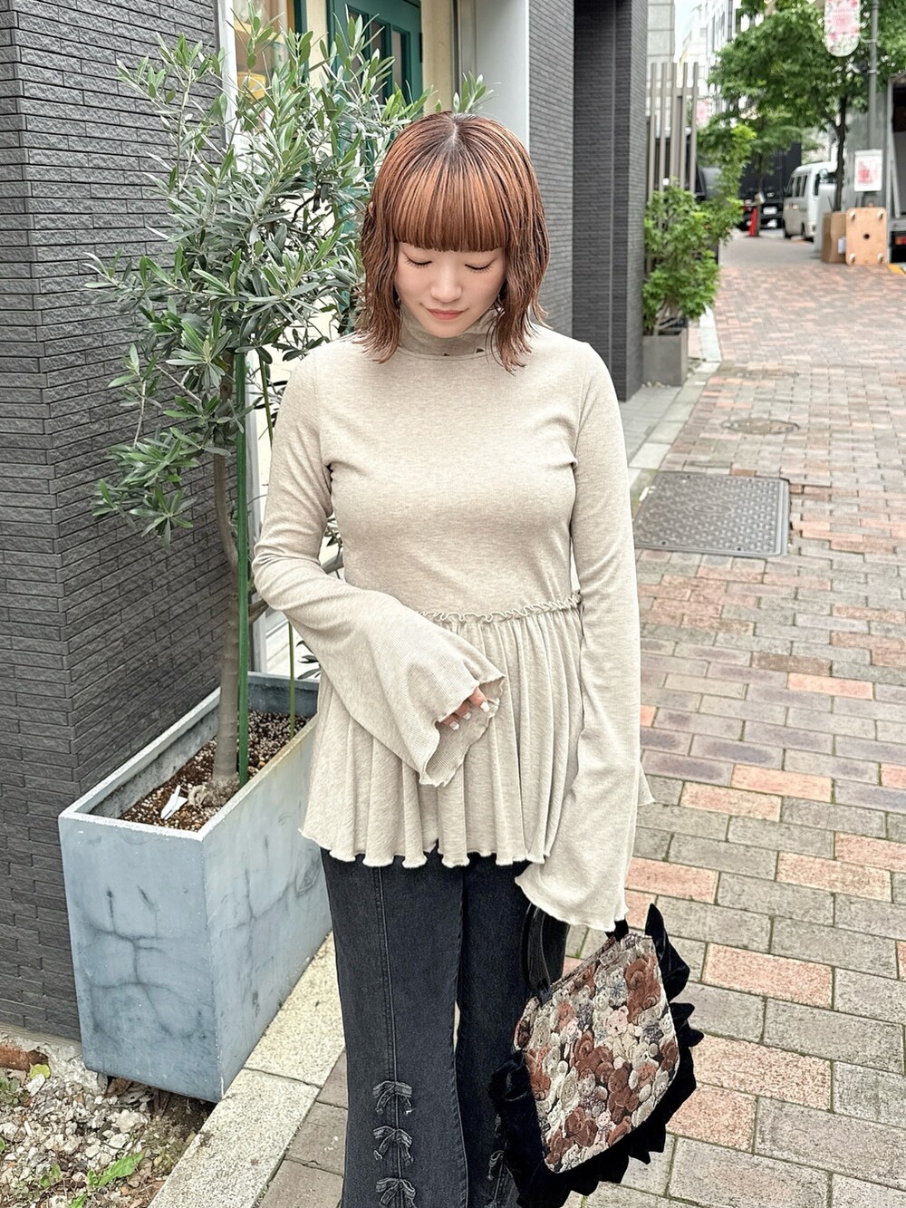 ブラウン系のニット/セーター、ブラック系のハンドバッグ、ブラック系のデニムパンツを着用したレディースの夏コーディネートの3枚目の写真