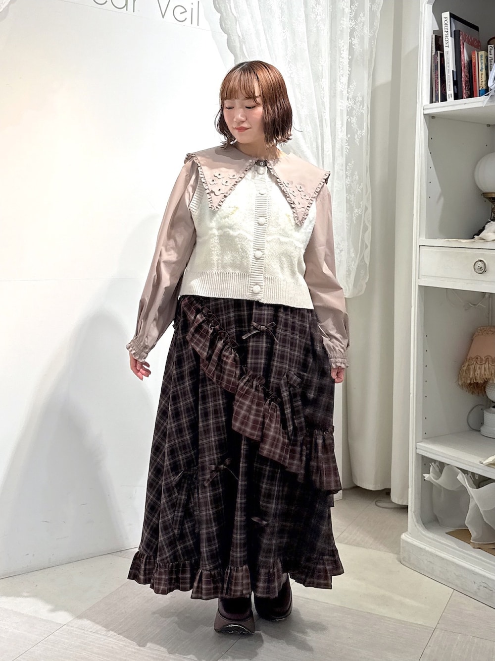 ベージュ系のシャツ/ブラウス、ピンク系のベスト、レッド系のスカートを着用したレディースの夏コーディネートの2枚目の写真
