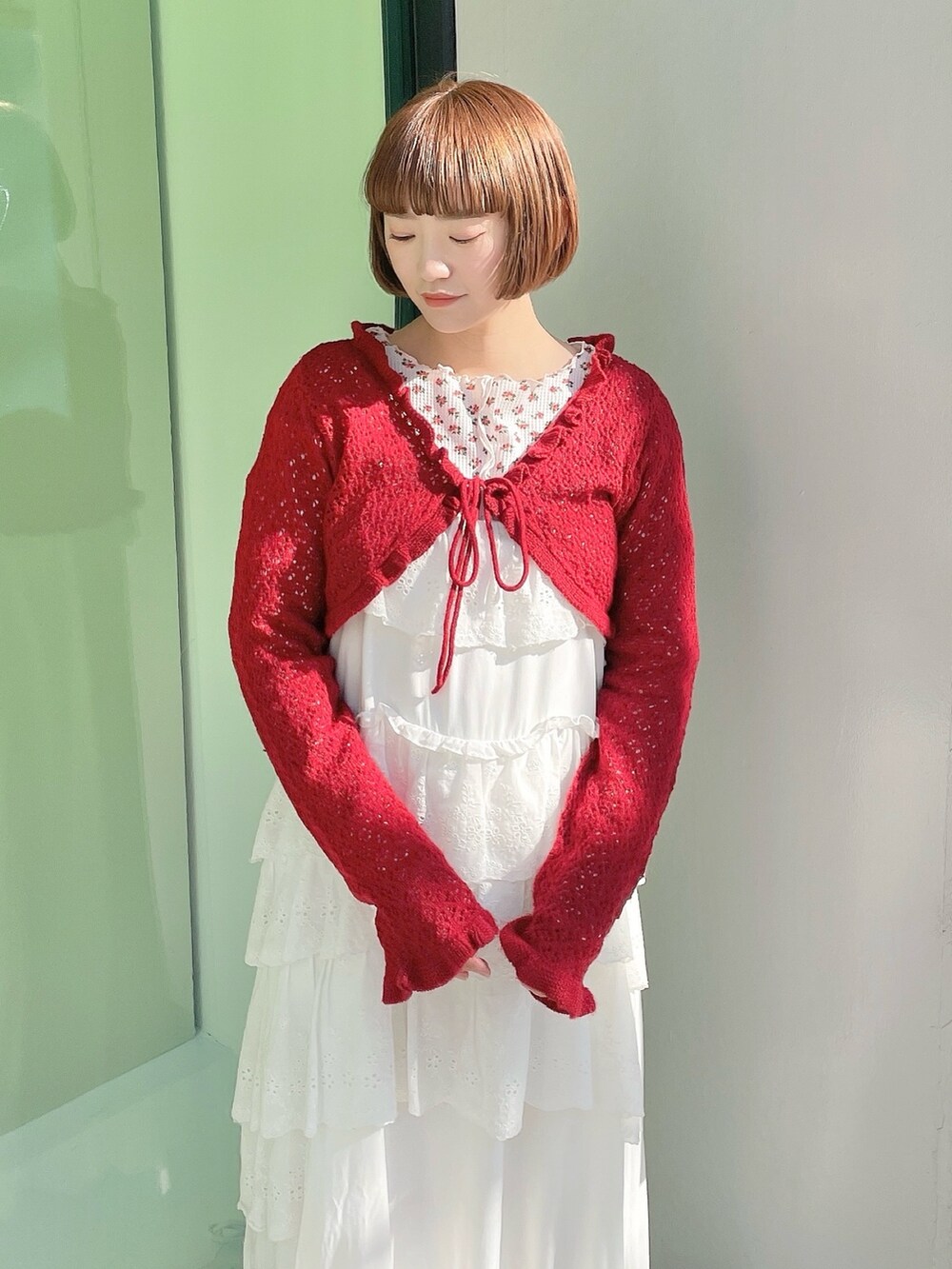 ピンク系のTシャツ/カットソー、レッド系のカーディガン/ボレロ、ホワイト系のワンピースを着用したレディースの冬コーディネートの4枚目の写真