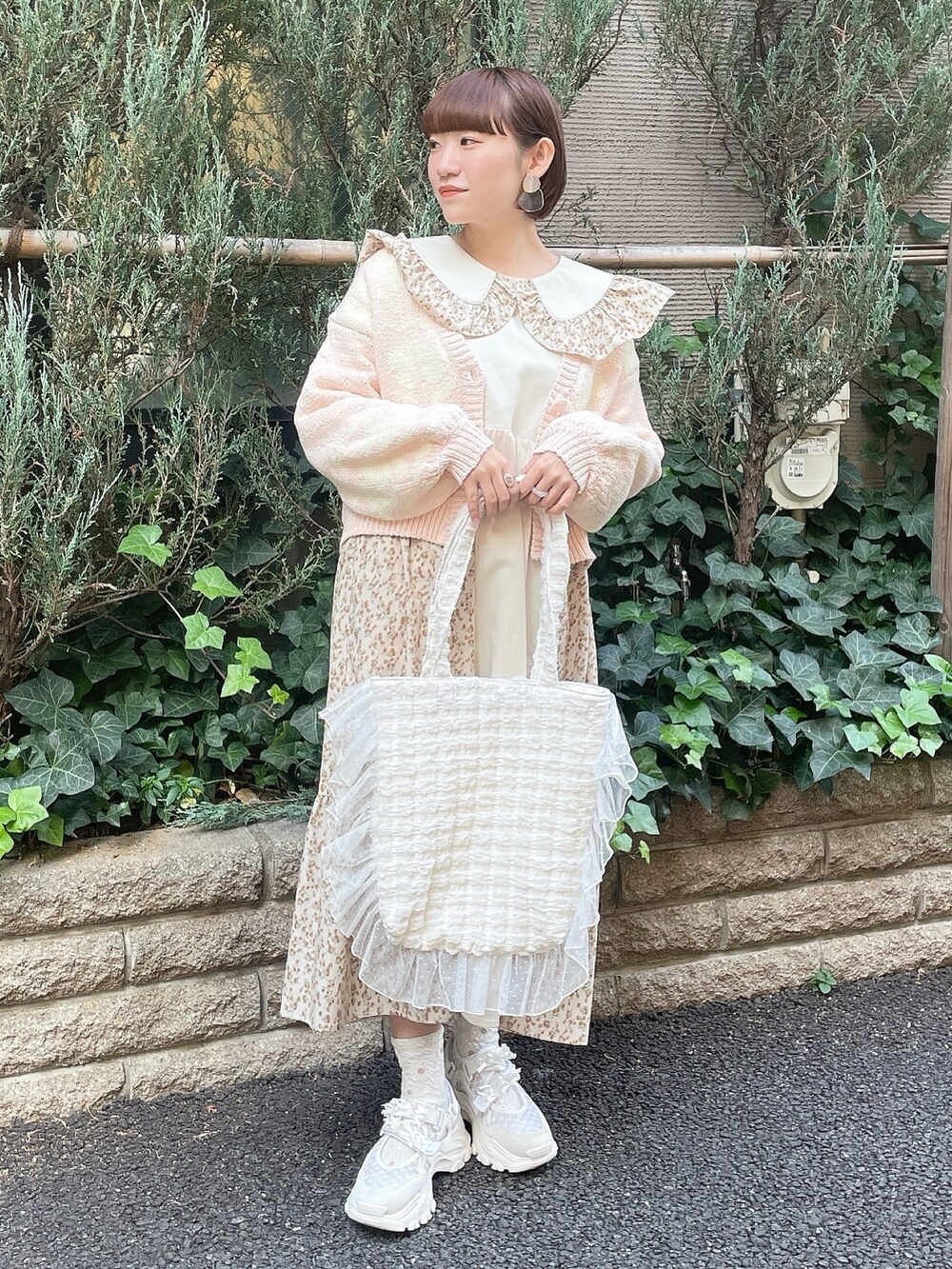 ベージュ系のワンピース、ピンク系のカーディガン/ボレロ、ホワイト系のトートバッグを着用したレディースの冬コーディネートの2枚目の写真