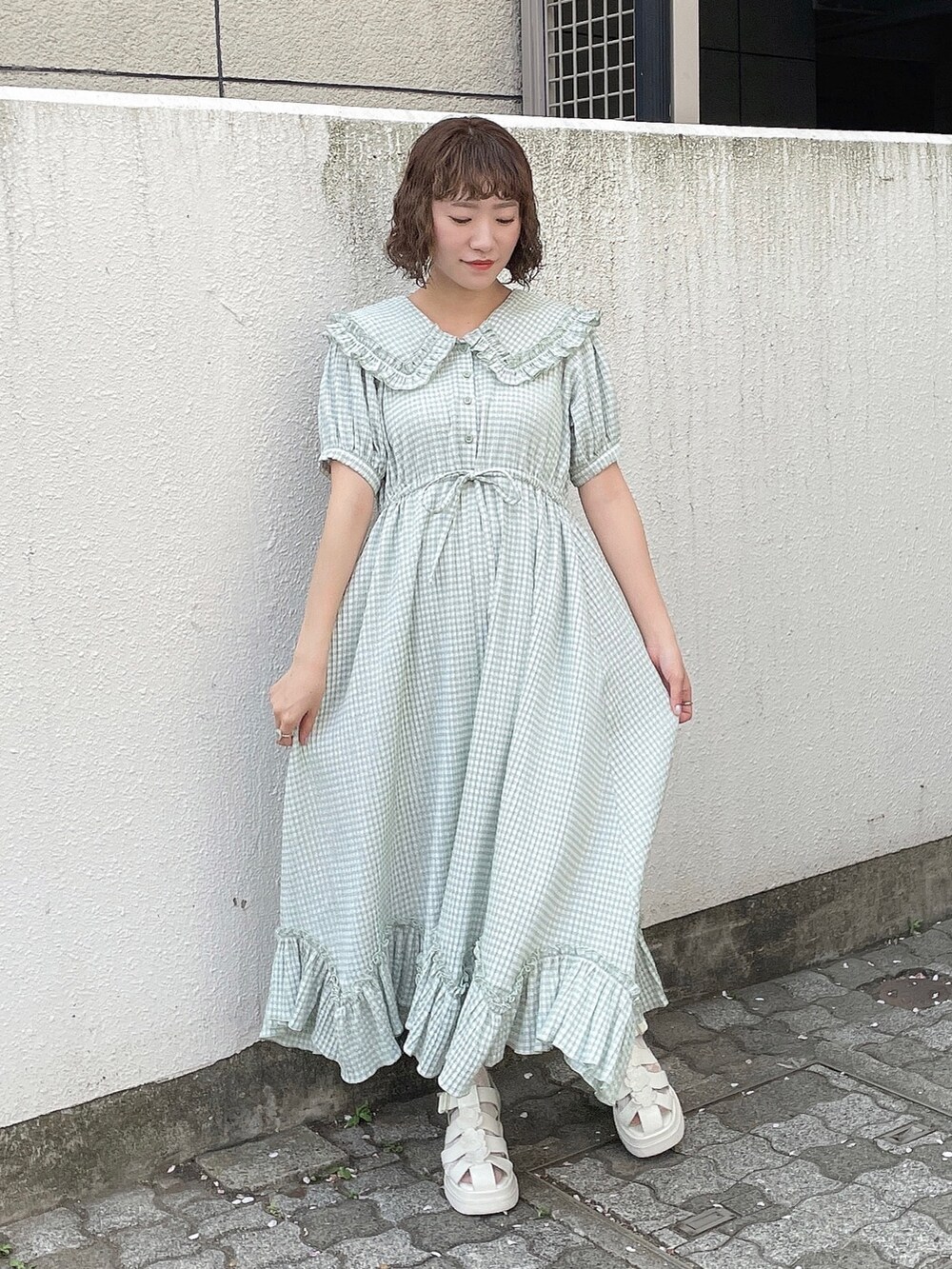 グリーン系のワンピース、ホワイト系のトートバッグ、ホワイト系のサンダルを着用したレディースの春コーディネートの5枚目の写真