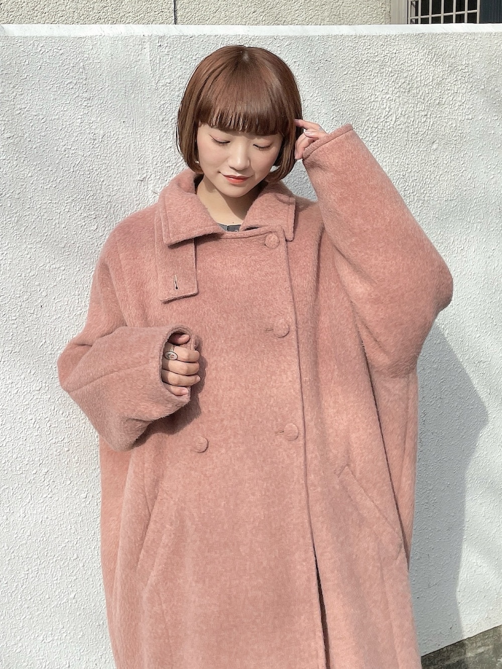 ピンク系のチェスターコート、ブラック系のスカート、グレー系のシャツ/ブラウスを着用したレディースの冬コーディネートの4枚目の写真