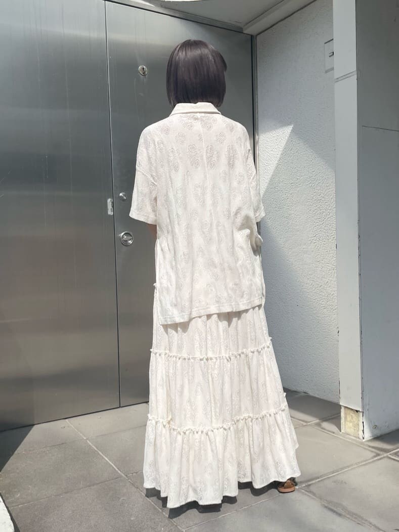 ホワイト系のスカート、ベージュ系のパンプス、ピンク系のハンドバッグを着用したレディースの春コーディネートの3枚目の写真