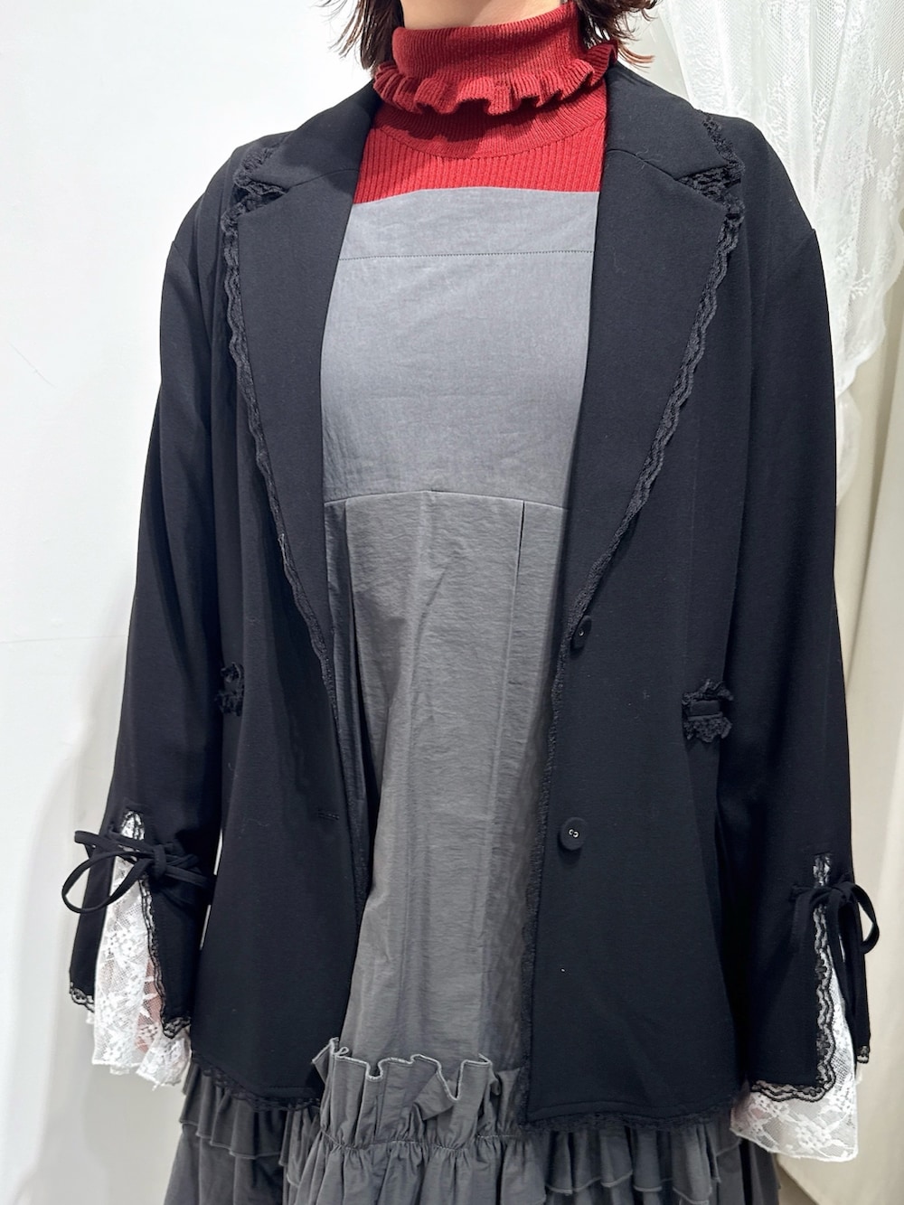 レッド系のニット/セーター、グレー系のワンピース、ブラック系のテーラードジャケットを着用したレディースの冬コーディネートの4枚目の写真