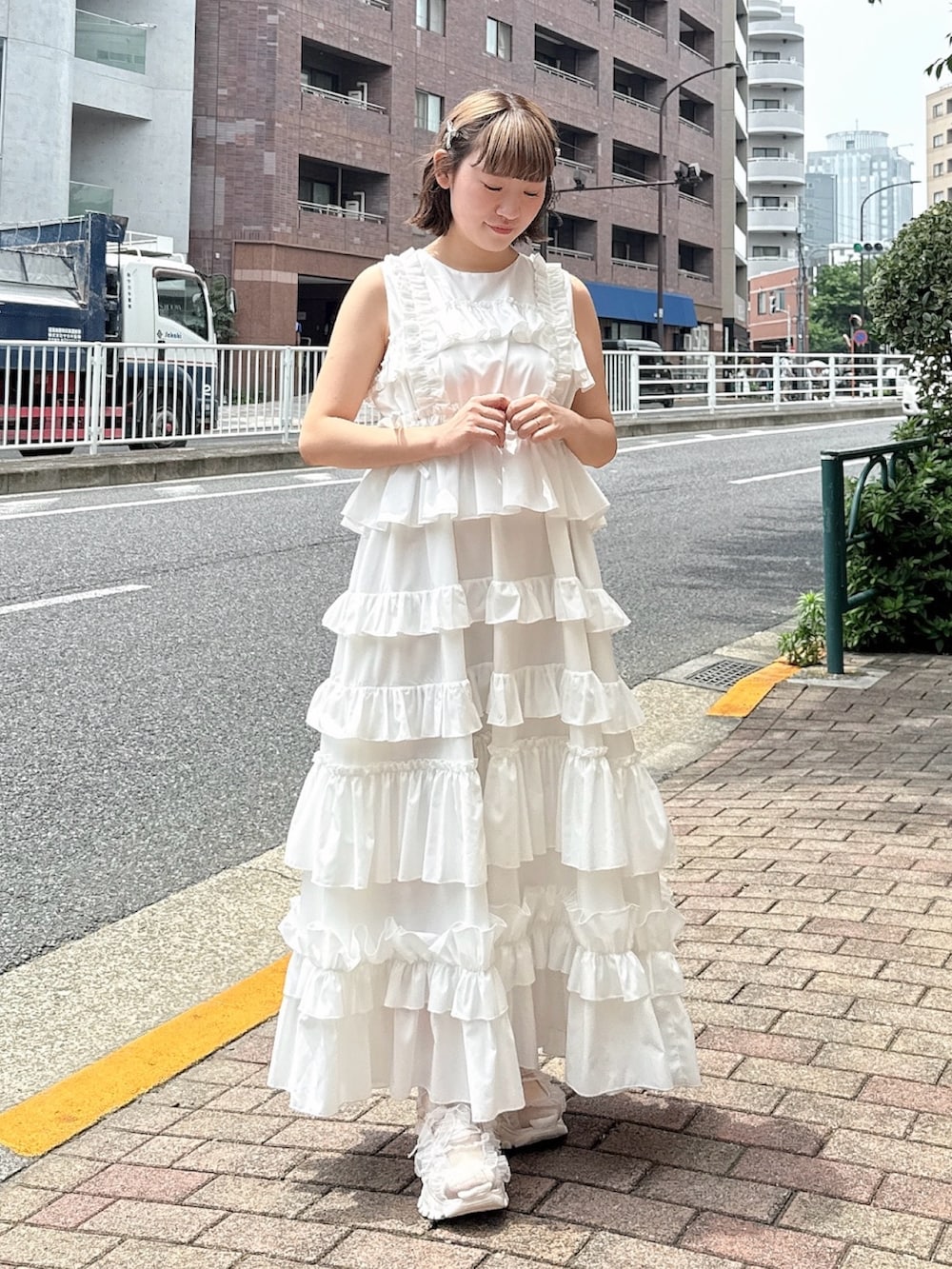 ホワイト系のワンピース、ピンク系のスニーカー、ピンク系の長傘を着用したレディースの春コーディネートの4枚目の写真