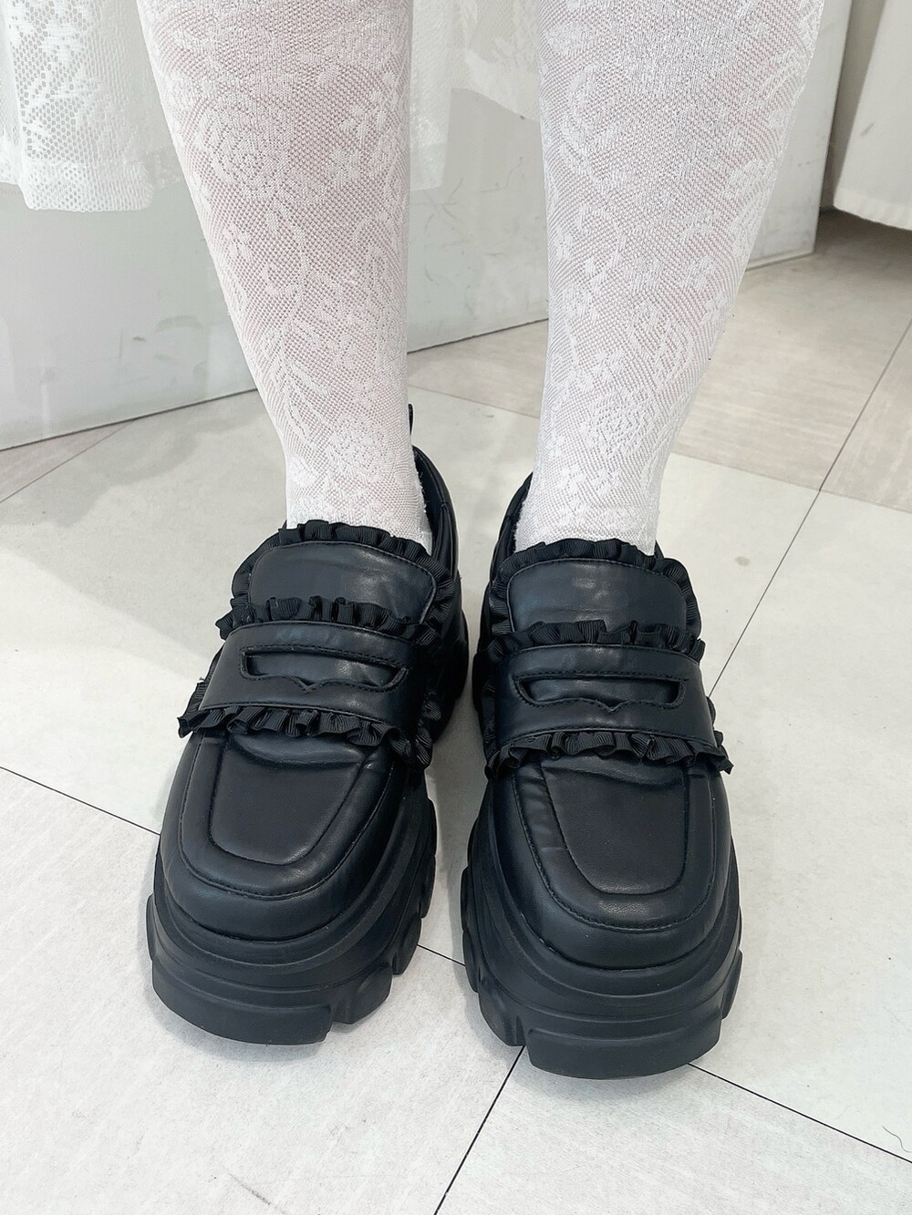 レッド系のニット/セーター、ブラック系のスウェットパンツ、ブラック系のローファーを着用したレディースの秋コーディネートの6枚目の写真