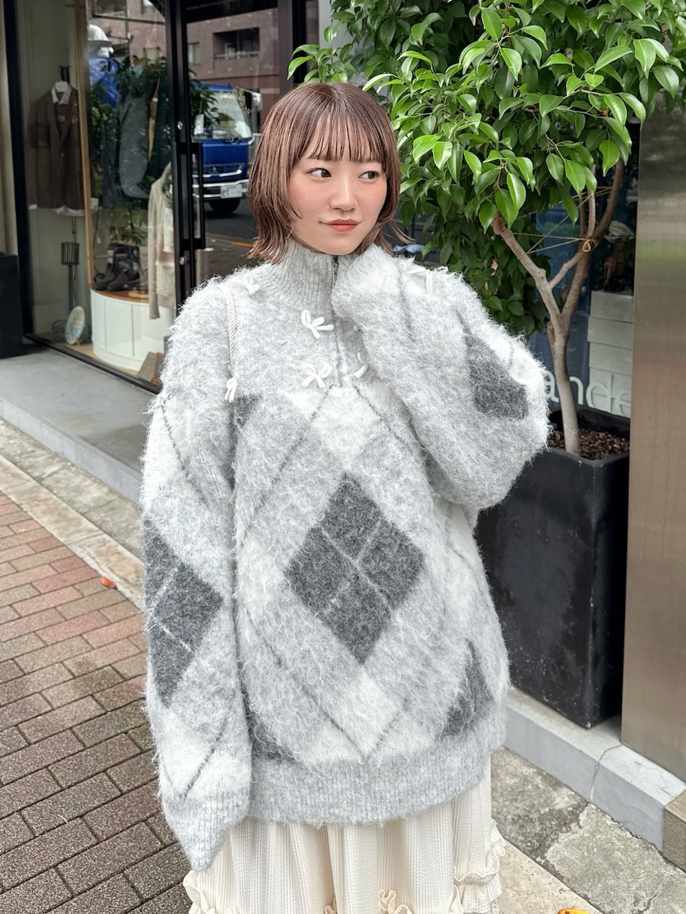 ホワイト系のスカート、グレー系のニット/セーター、ホワイト系のバックパック/リュックを着用したレディースの秋コーディネートの4枚目の写真