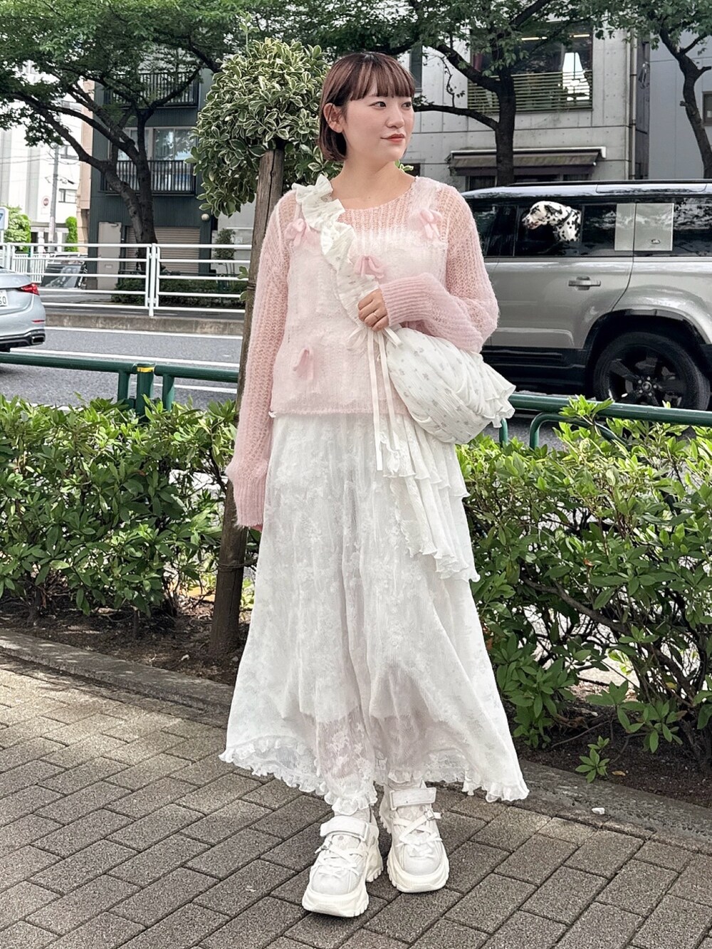 ピンク系のニット/セーター、ホワイト系のショルダーバッグ、ホワイト系のワンピースを着用したレディースの夏コーディネートの2枚目の写真