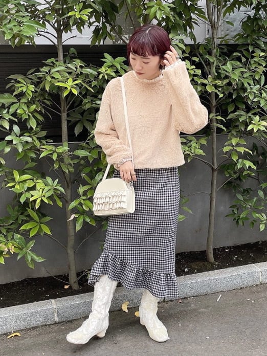 ホワイト系のブーツ、ブラック系のスカート、ホワイト系のショルダーバッグを着用したレディースの冬コーディネートの2枚目の写真