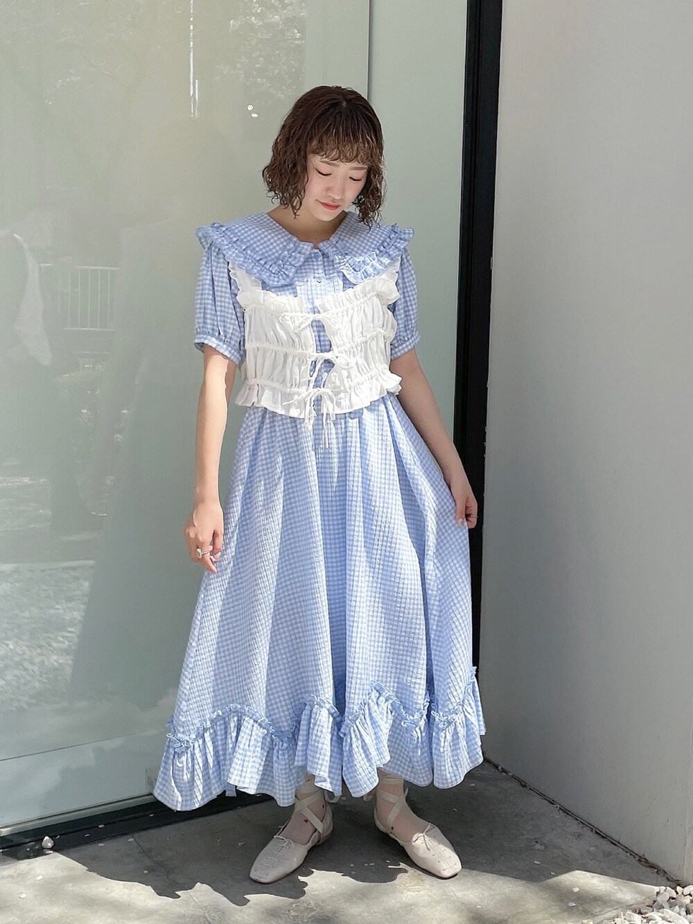 ブルー系のワンピース、ホワイト系のハンドバッグ、ホワイト系のベストを着用したレディースの春コーディネートの3枚目の写真