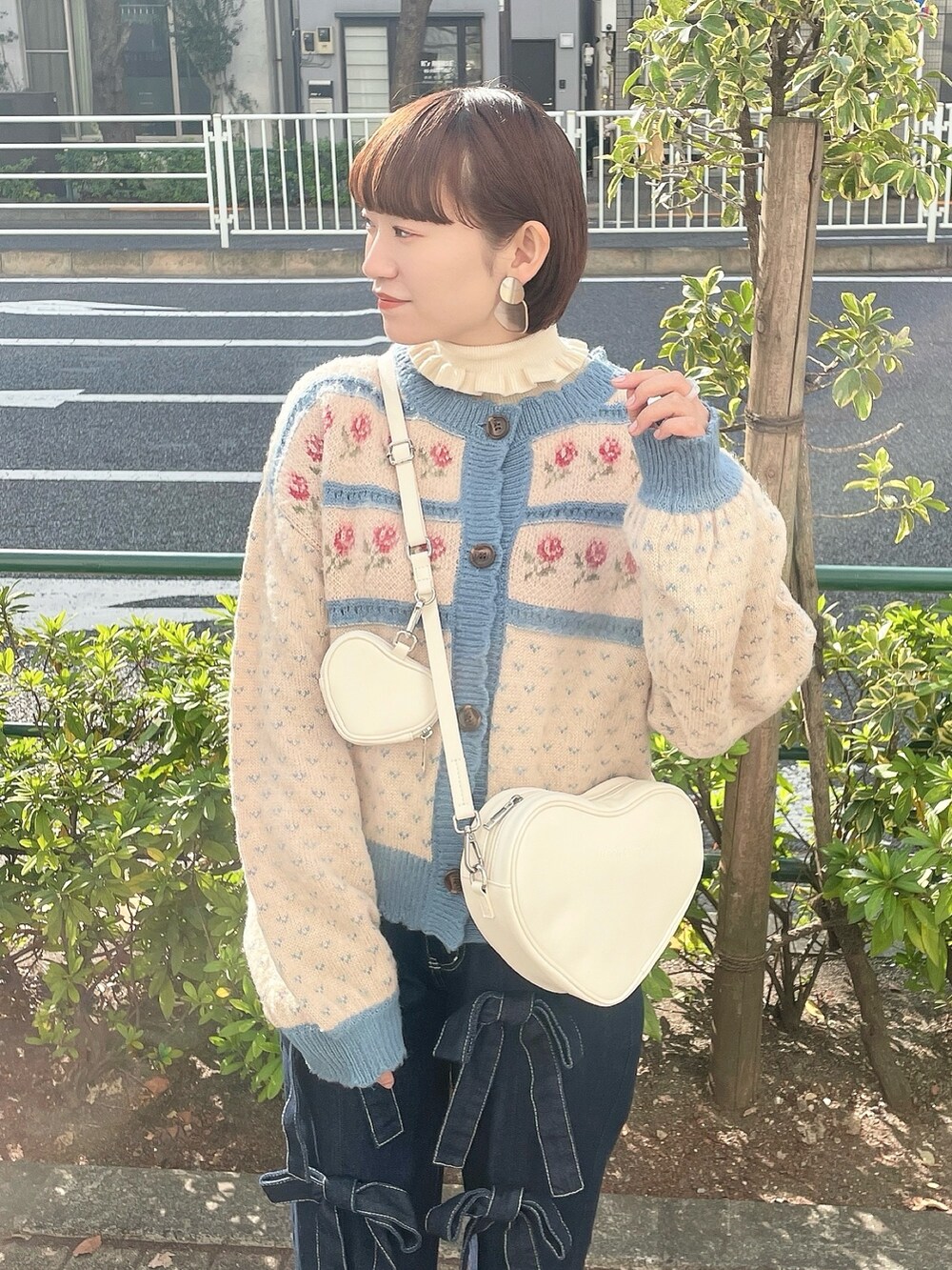 ホワイト系のハンドバッグ、ホワイト系のニット/セーター、ブルー系のカーディガン/ボレロを着用したレディースの冬コーディネートの3枚目の写真