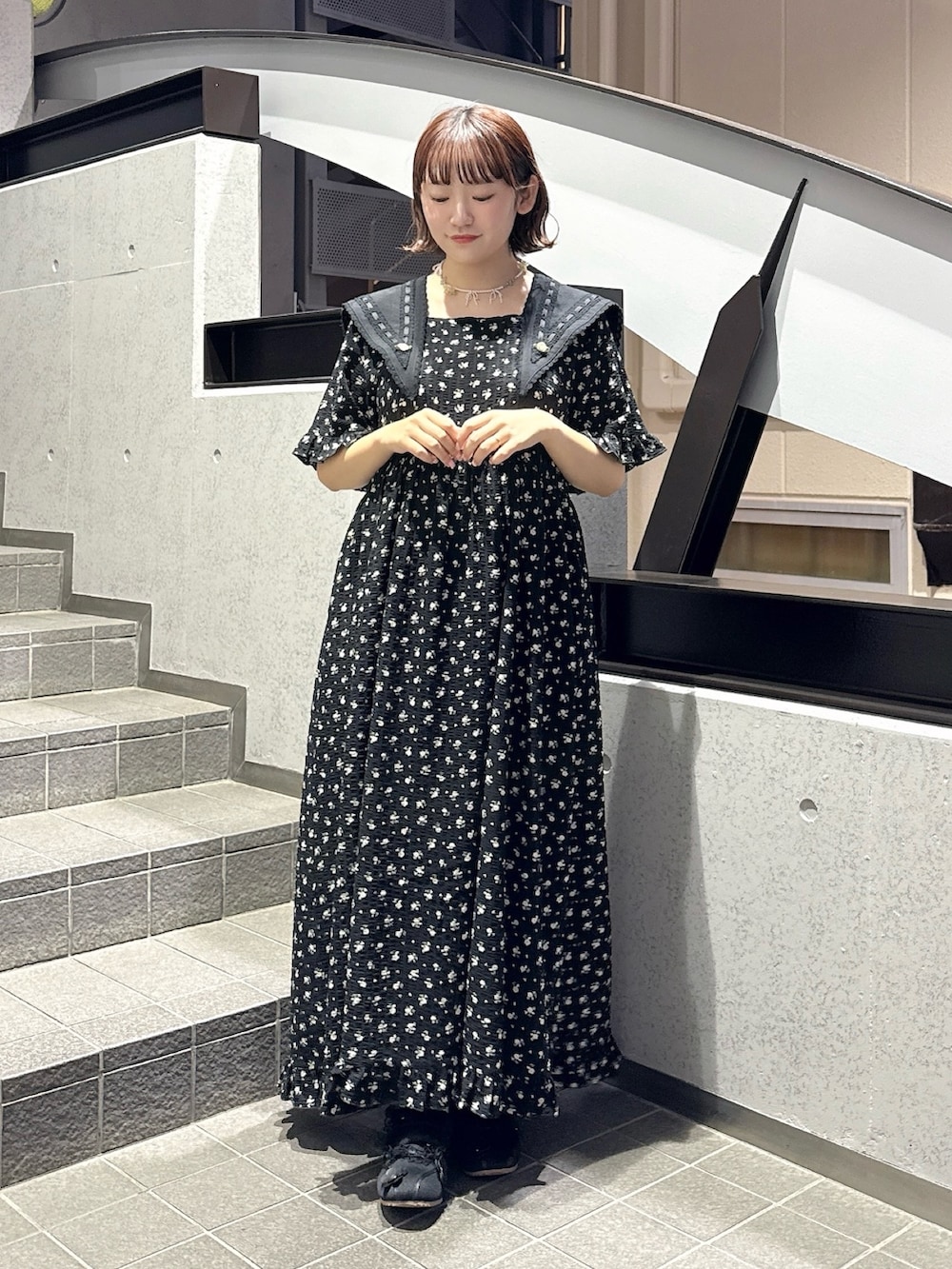 ブラック系のワンピース、ブラック系のスニーカー、ピンク系のネックレスを着用したレディースの春コーディネートの2枚目の写真