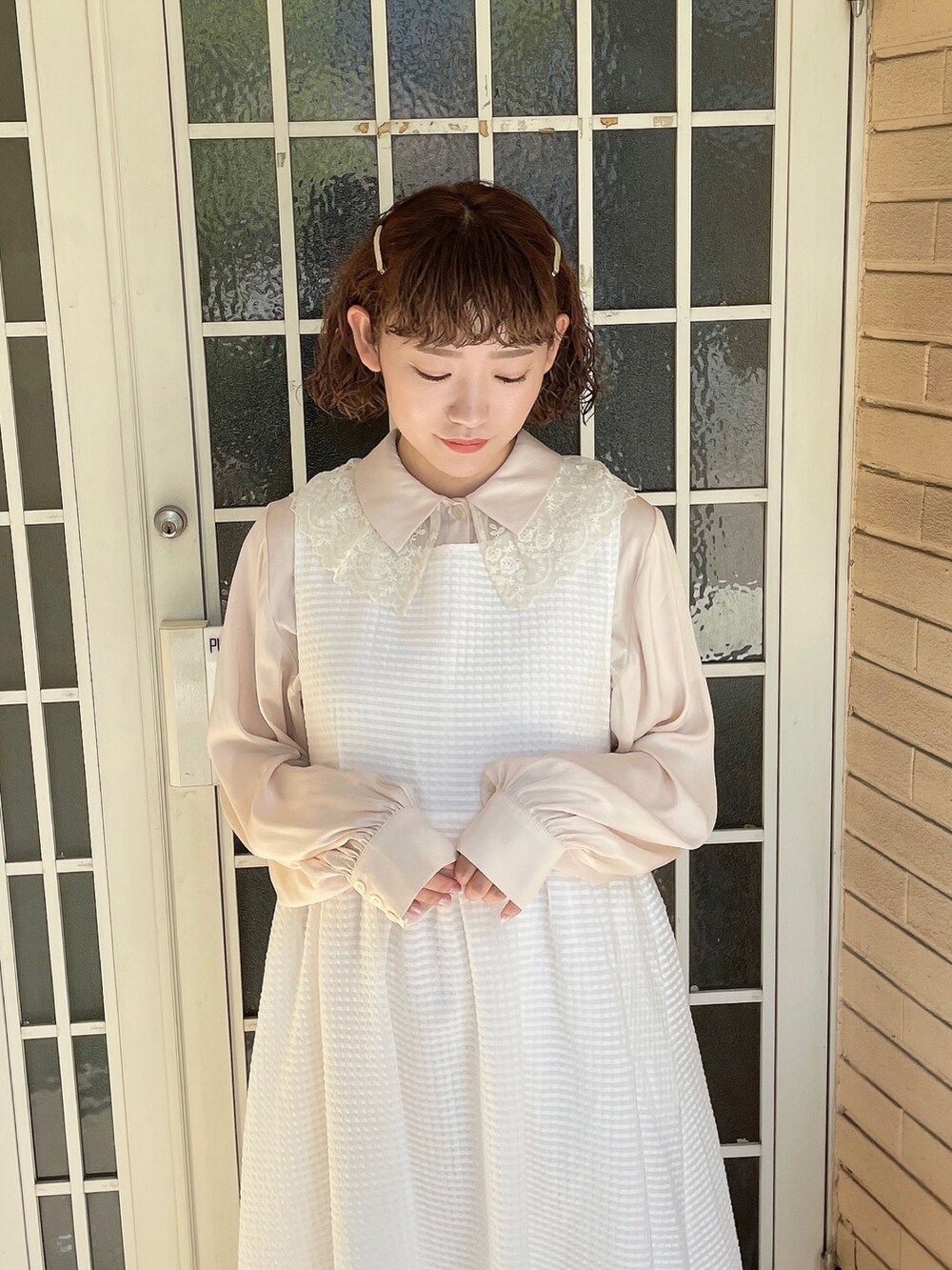 ゴールド系のパンプス、ホワイト系のチュニック、ホワイト系のワンピースを着用したレディースの春コーディネートの4枚目の写真