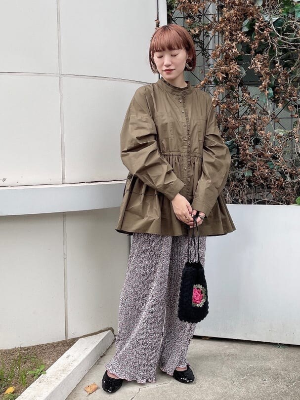 ブラック系のハンドバッグ、グリーン系のワンピース、ブラック系のパンプスを着用したレディースの秋コーディネートの2枚目の写真