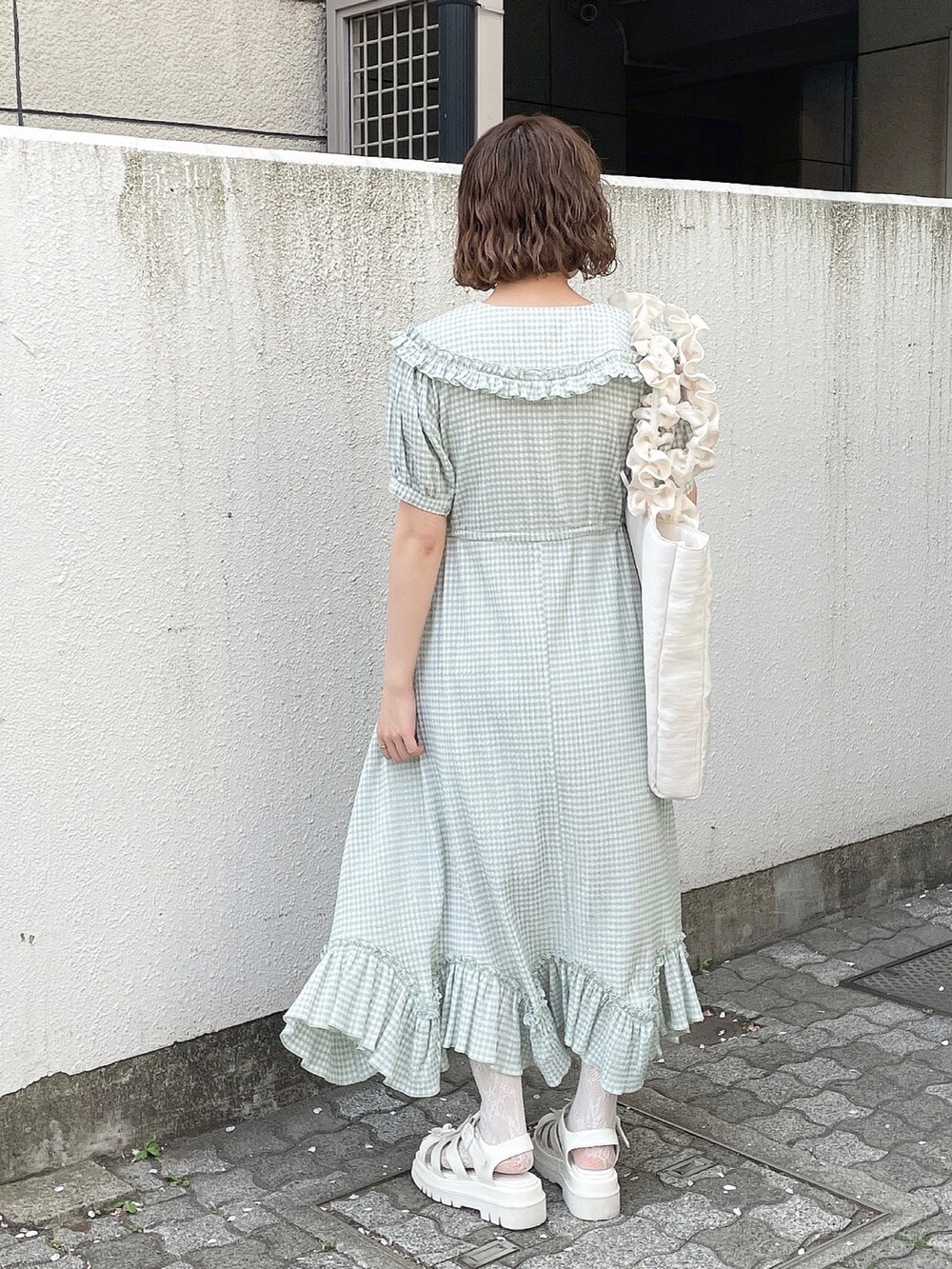 グリーン系のワンピース、ホワイト系のトートバッグ、ホワイト系のサンダルを着用したレディースの春コーディネートの4枚目の写真