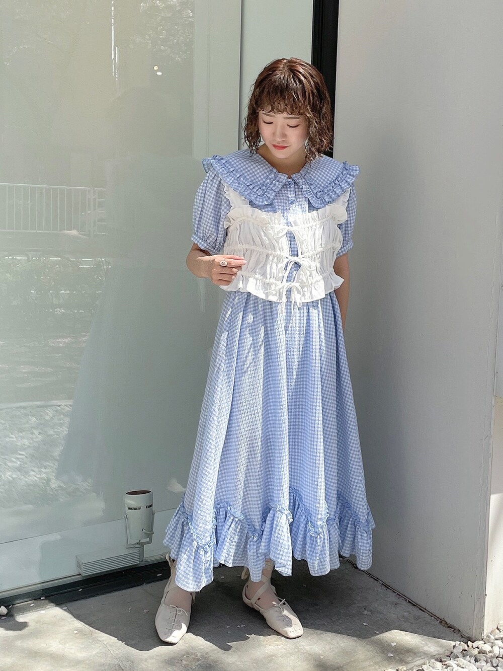 ブルー系のワンピース、ホワイト系のハンドバッグ、ホワイト系のベストを着用したレディースの春コーディネートの4枚目の写真