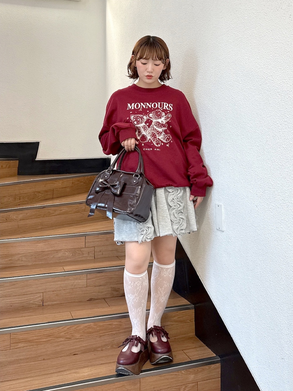 レッド系のスウェット、グレー系のスカート、ブラウン系のハンドバッグを着用したレディースの夏コーディネートの2枚目の写真
