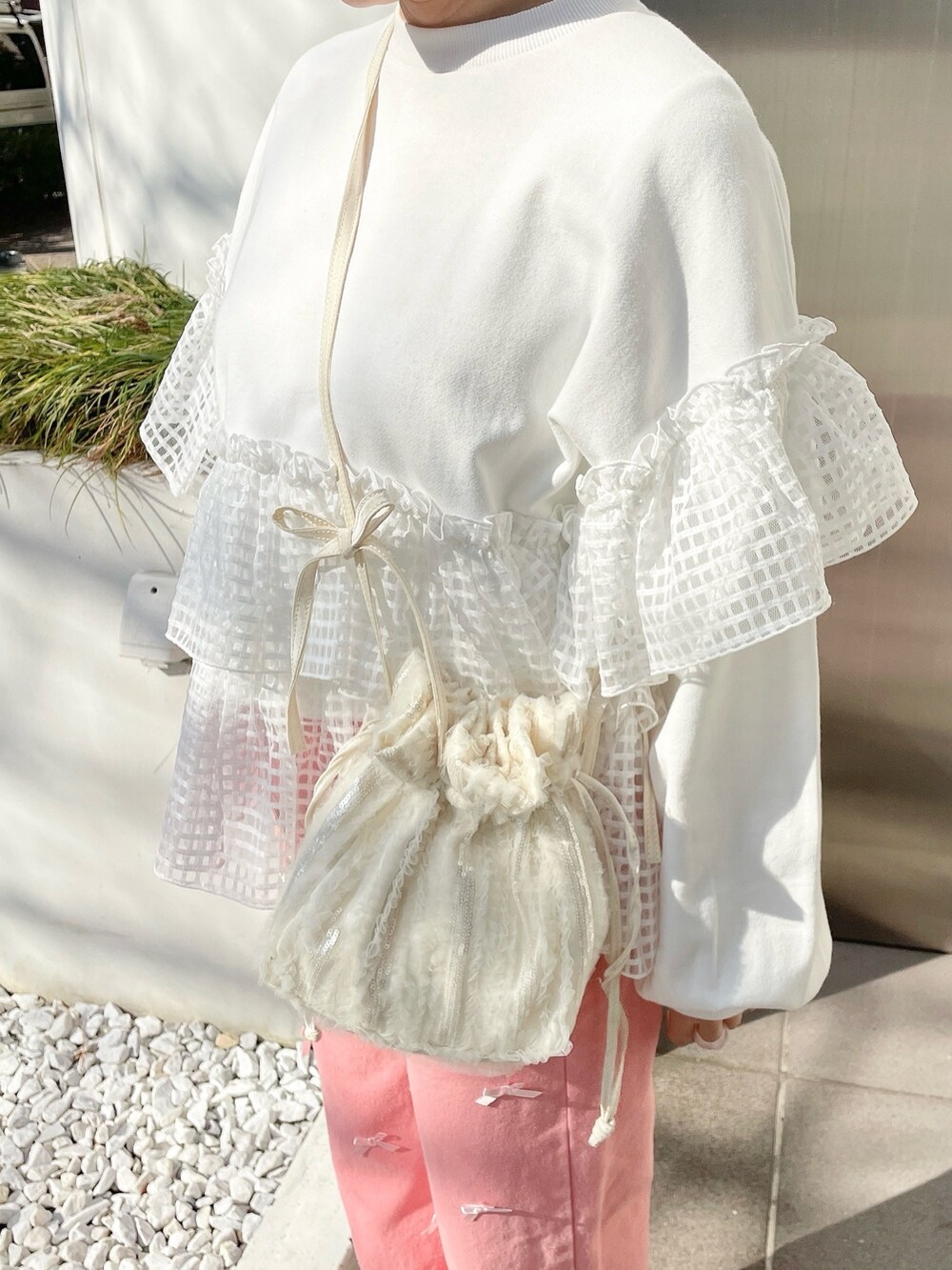 ホワイト系のスウェット、ピンク系のデニムパンツ、ホワイト系のショルダーバッグを着用したレディースの冬コーディネートの6枚目の写真