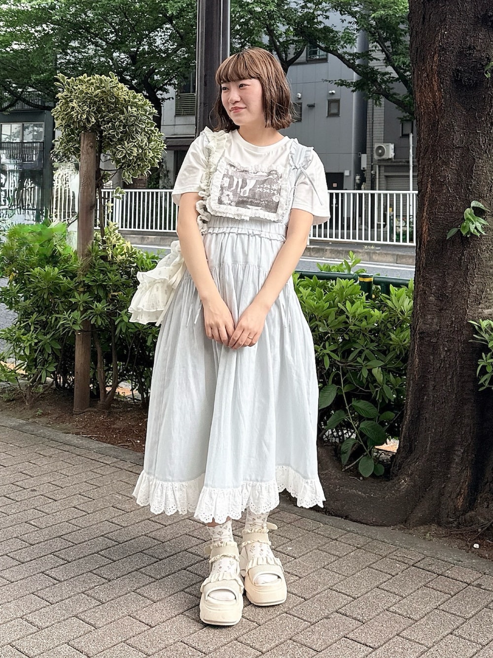 ホワイト系のTシャツ/カットソー、グリーン系のジャンパースカート、ホワイト系のショルダーバッグを着用したレディースの春コーディネートの2枚目の写真
