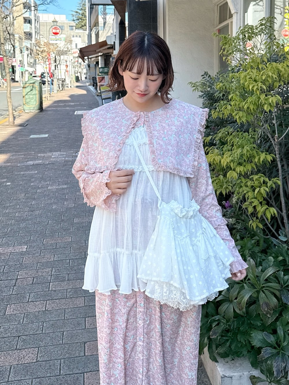 ピンク系のワンピース、ホワイト系のショルダーバッグ、ホワイト系のチュニックを着用したレディースの冬コーディネートの3枚目の写真