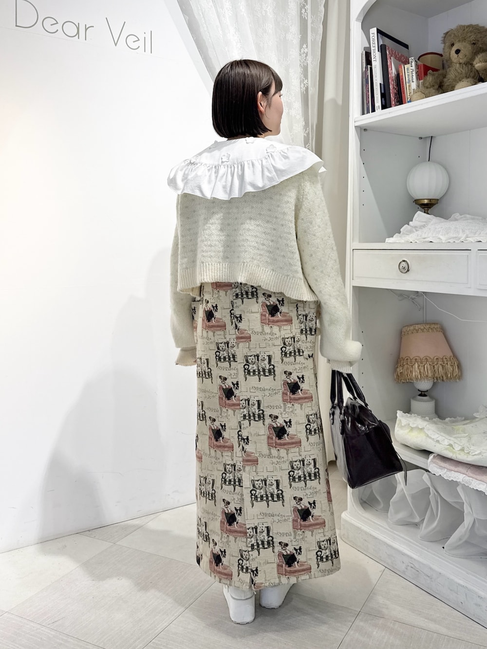 ベージュ系のジャンパースカート、ホワイト系のシャツ/ブラウス、ホワイト系のカーディガン/ボレロを着用したレディースの夏コーディネートの4枚目の写真