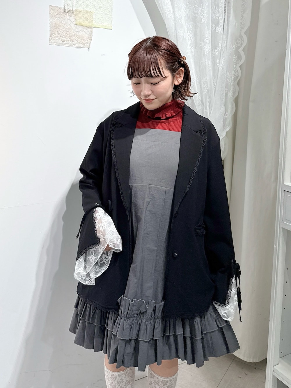 レッド系のニット/セーター、グレー系のワンピース、ブラック系のテーラードジャケットを着用したレディースの冬コーディネートの3枚目の写真