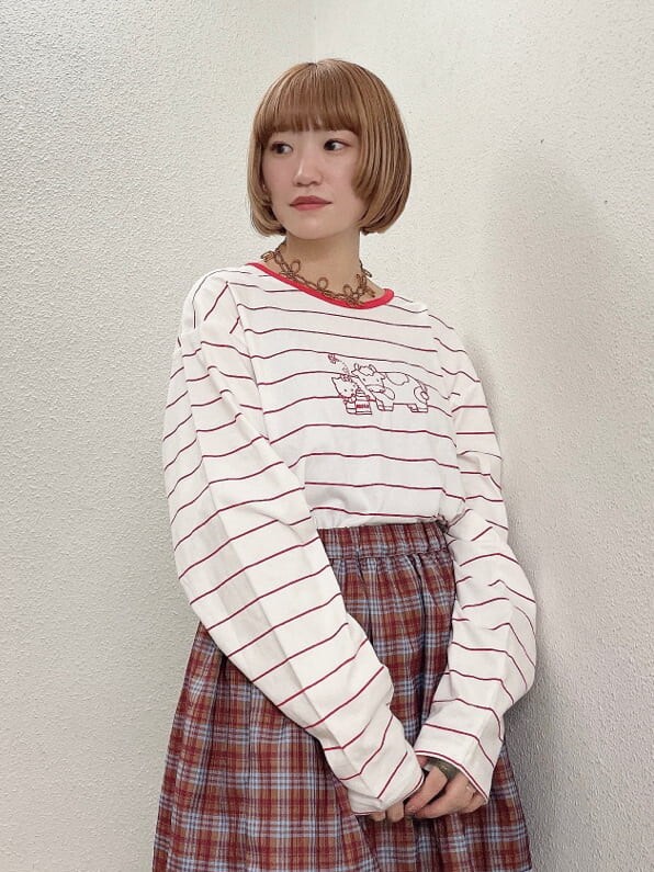 レッド系のTシャツ/カットソー、オレンジ系のスカート、ホワイト系のローファーを着用したレディースの秋コーディネートの5枚目の写真
