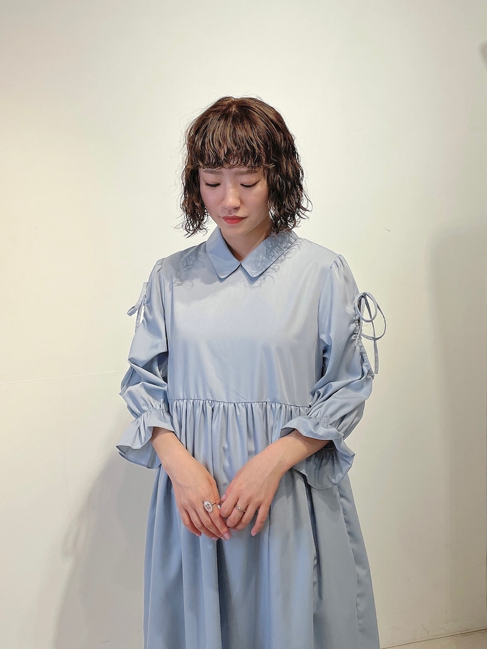 ホワイト系のトートバッグ、ブルー系のワンピース、ゴールド系のパンプスを着用したレディースの春コーディネートの4枚目の写真