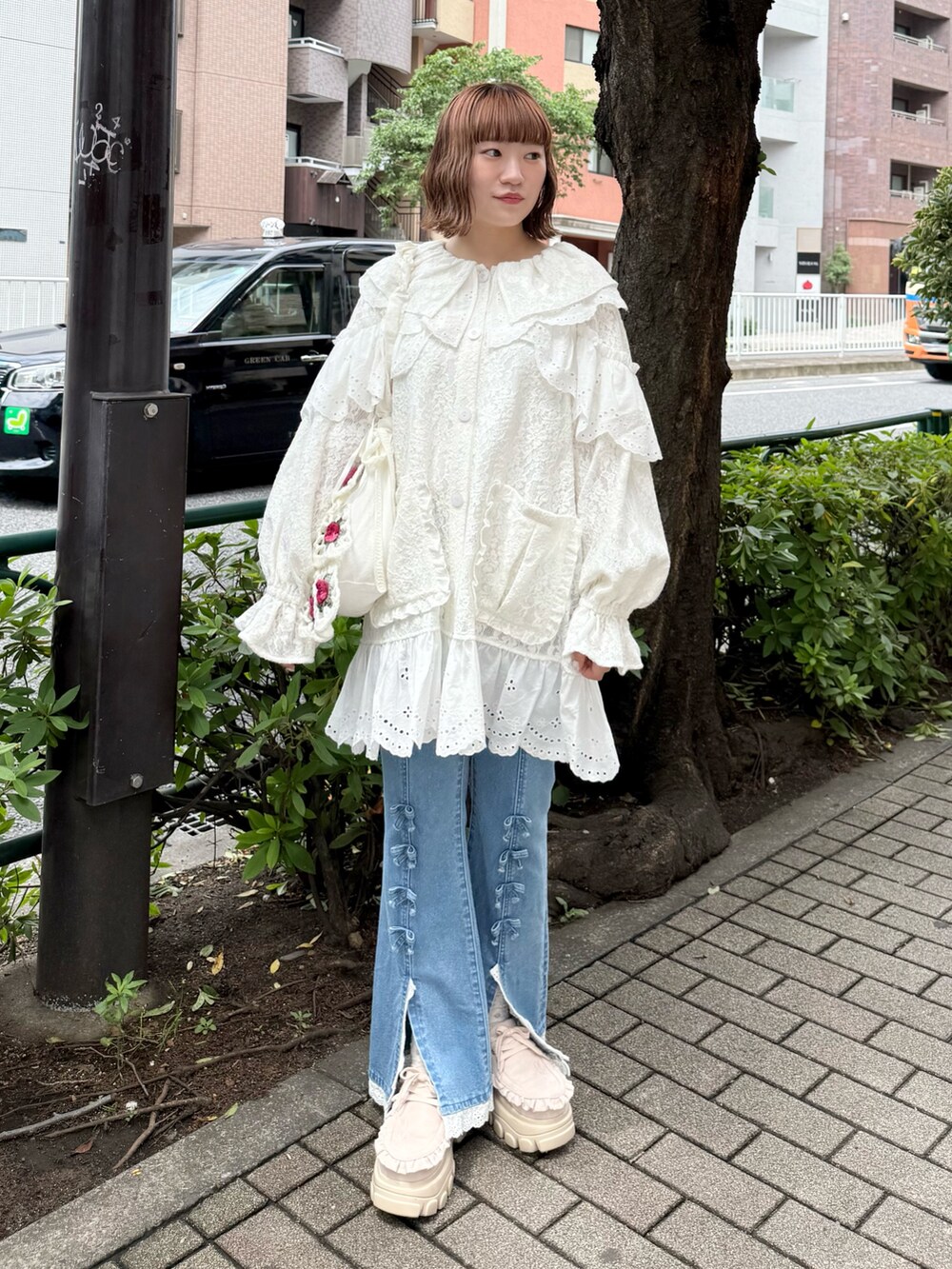 ホワイト系のテーラードジャケット、ブルー系のデニムパンツ、ホワイト系のショルダーバッグを着用したレディースの夏コーディネートの2枚目の写真