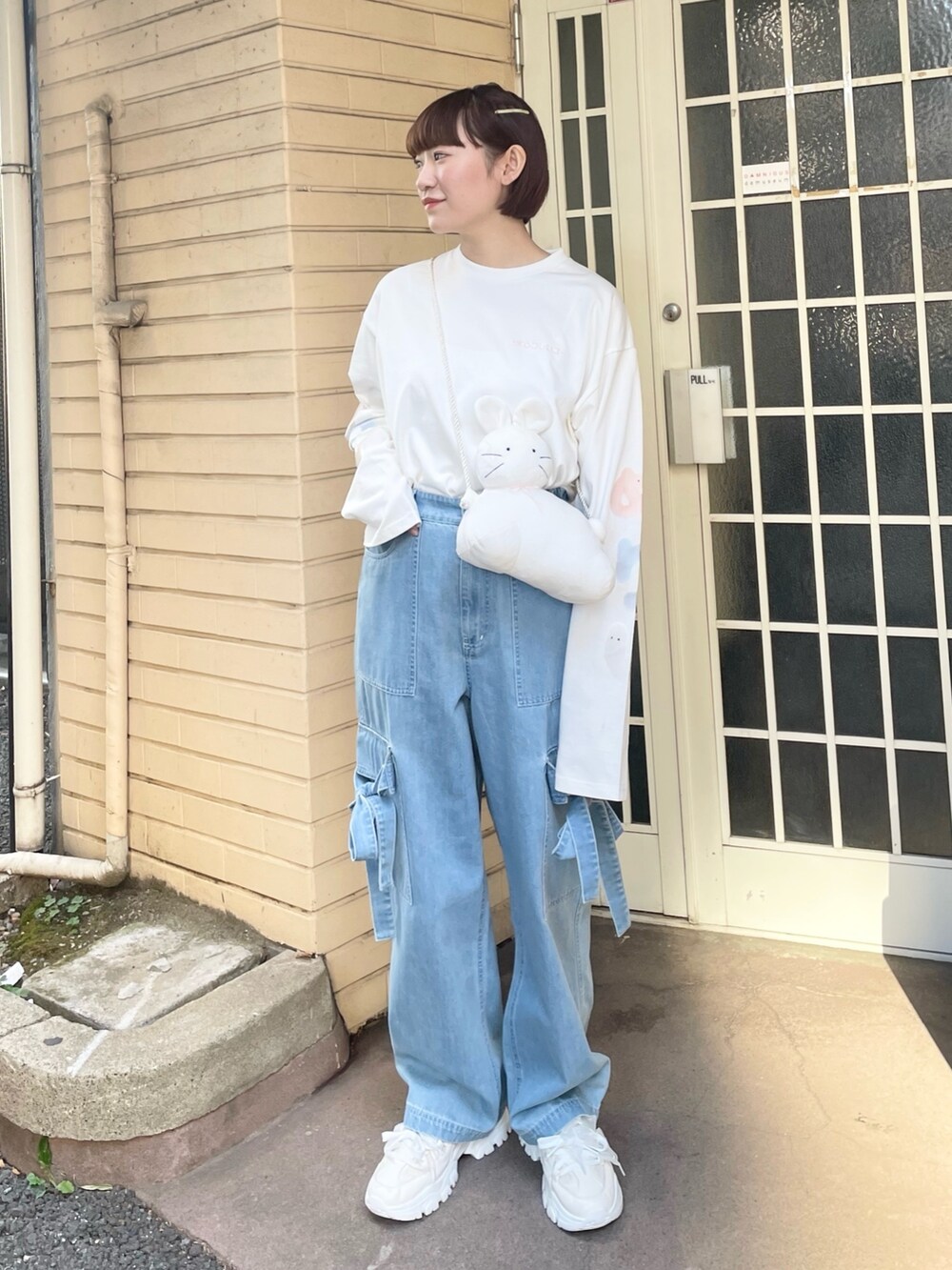 ホワイト系のTシャツ/カットソー、ホワイト系のショルダーバッグ、ブルー系のデニムパンツを着用したレディースの冬コーディネートの3枚目の写真