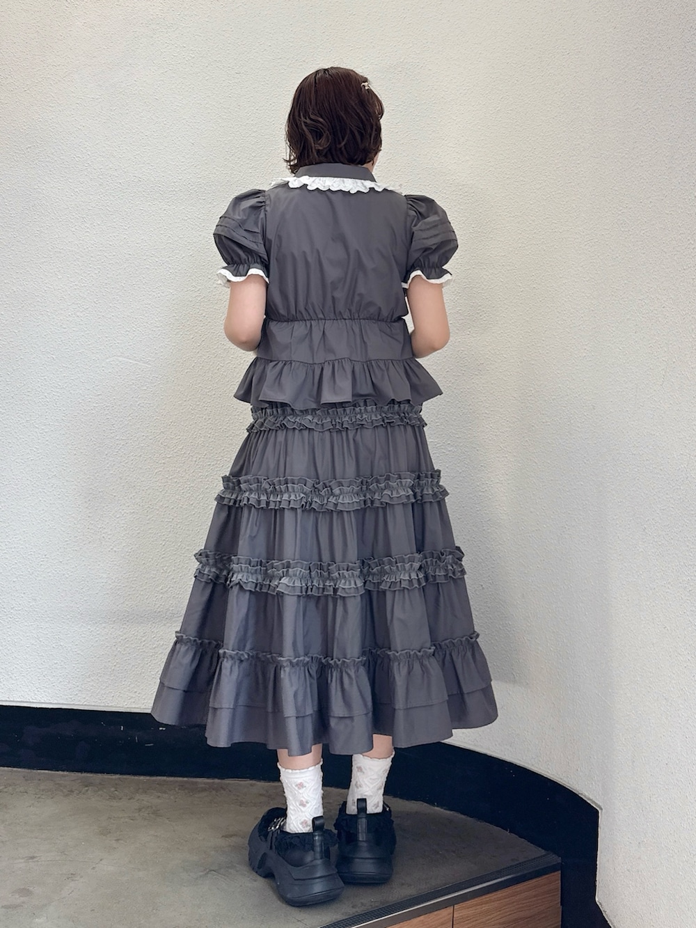 グレー系のシャツ/ブラウス、グレー系のスカート、ブラック系のスニーカーを着用したレディースの春コーディネートの3枚目の写真