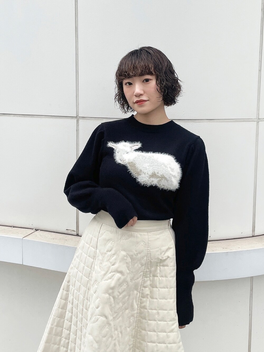 ブラック系のニット/セーター、ホワイト系のハンドバッグ、ホワイト系のスカートを着用したレディースの秋コーディネートの7枚目の写真