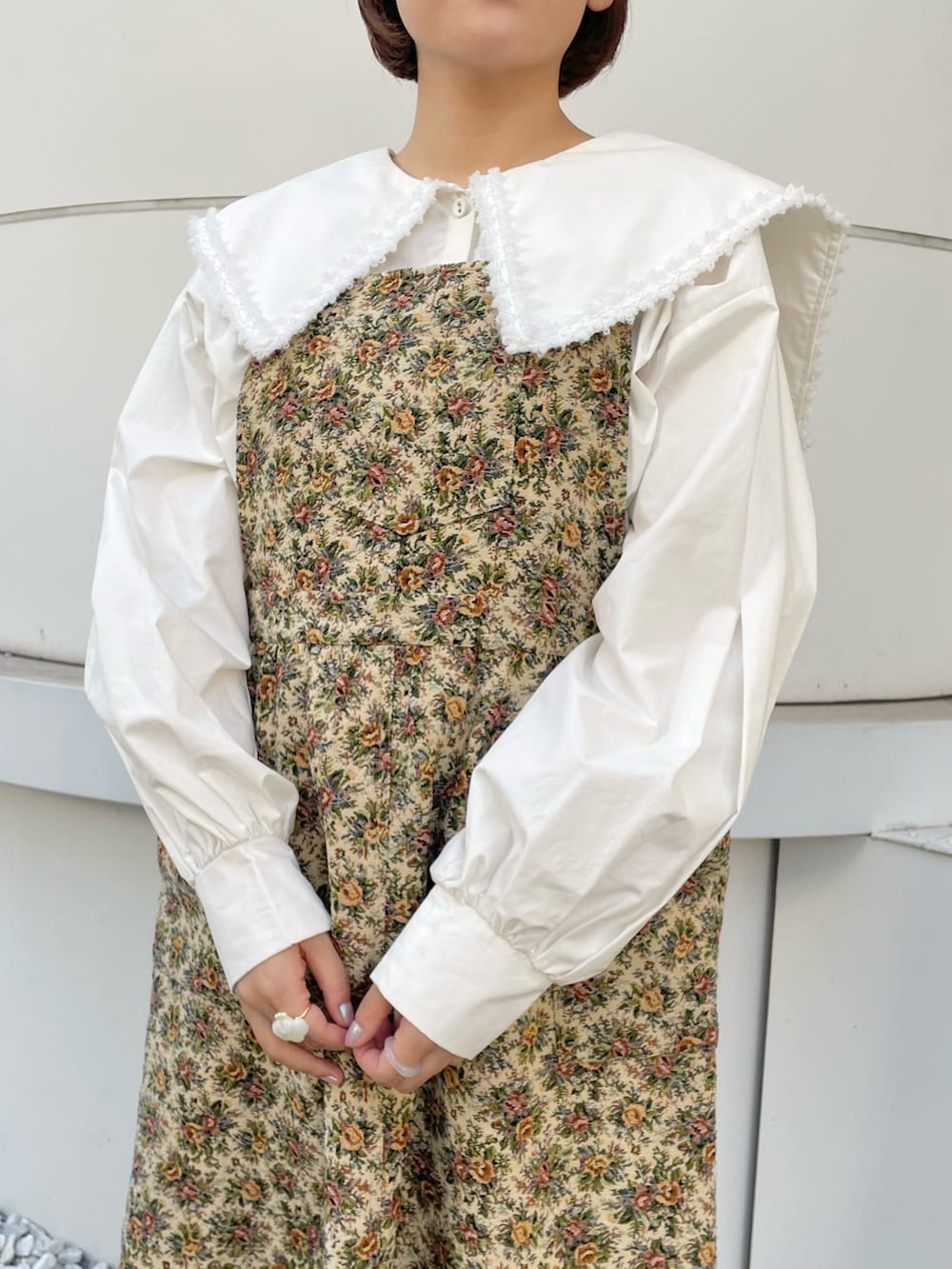 ホワイト系のシャツ/ブラウス、ベージュ系のジャンパースカート、ホワイト系のブーツを着用したレディースの秋コーディネートの5枚目の写真