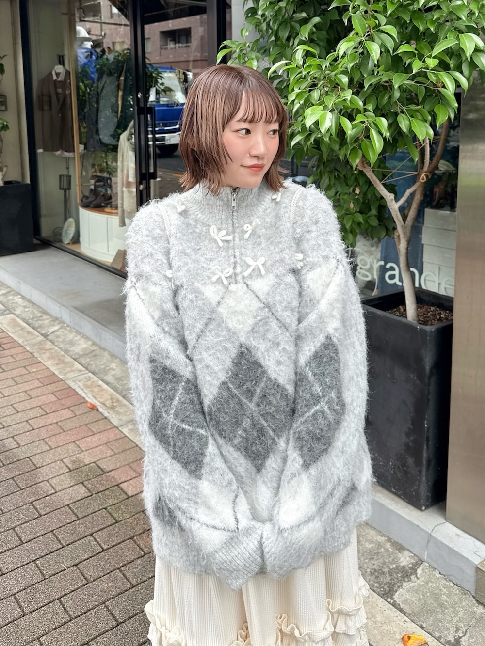 ホワイト系のスカート、グレー系のニット/セーター、ホワイト系のバックパック/リュックを着用したレディースの秋コーディネートの5枚目の写真