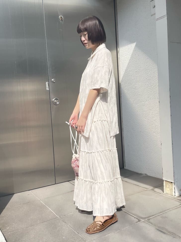 ホワイト系のスカート、ベージュ系のパンプス、ピンク系のハンドバッグを着用したレディースの春コーディネートの2枚目の写真