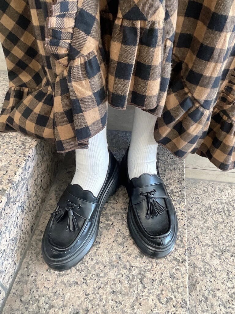 オレンジ系のスカート、ブラック系のローファー、ホワイト系のTシャツ/カットソーを着用したレディースの冬コーディネートの5枚目の写真