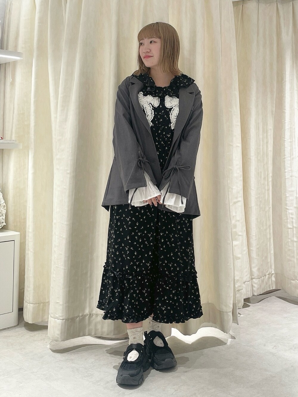 ブラック系のワンピース、グレー系のテーラードジャケット、ブラック系のスニーカーを着用したレディースの冬コーディネートの2枚目の写真