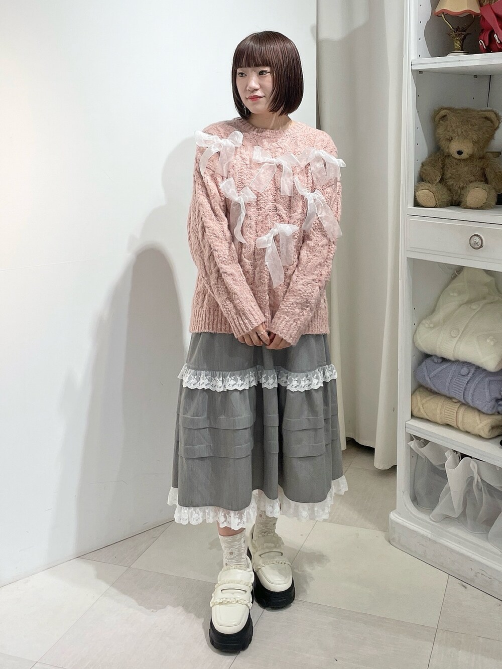 グレー系のスカート、ピンク系のニット/セーター、ホワイト系のローファーを着用したレディースの秋コーディネートの2枚目の写真