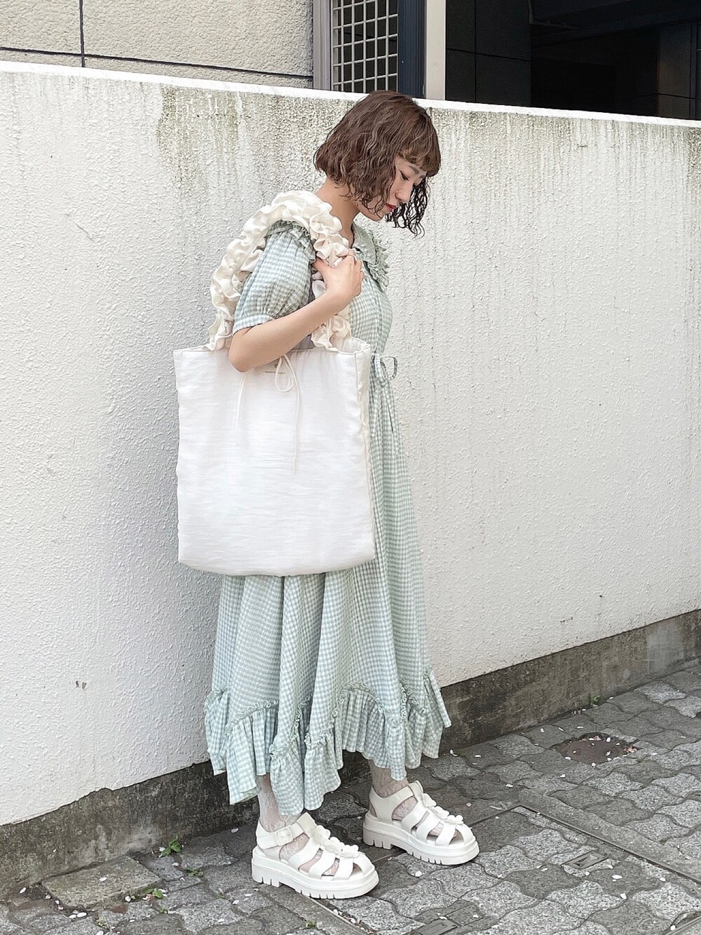 グリーン系のワンピース、ホワイト系のトートバッグ、ホワイト系のサンダルを着用したレディースの春コーディネートの3枚目の写真