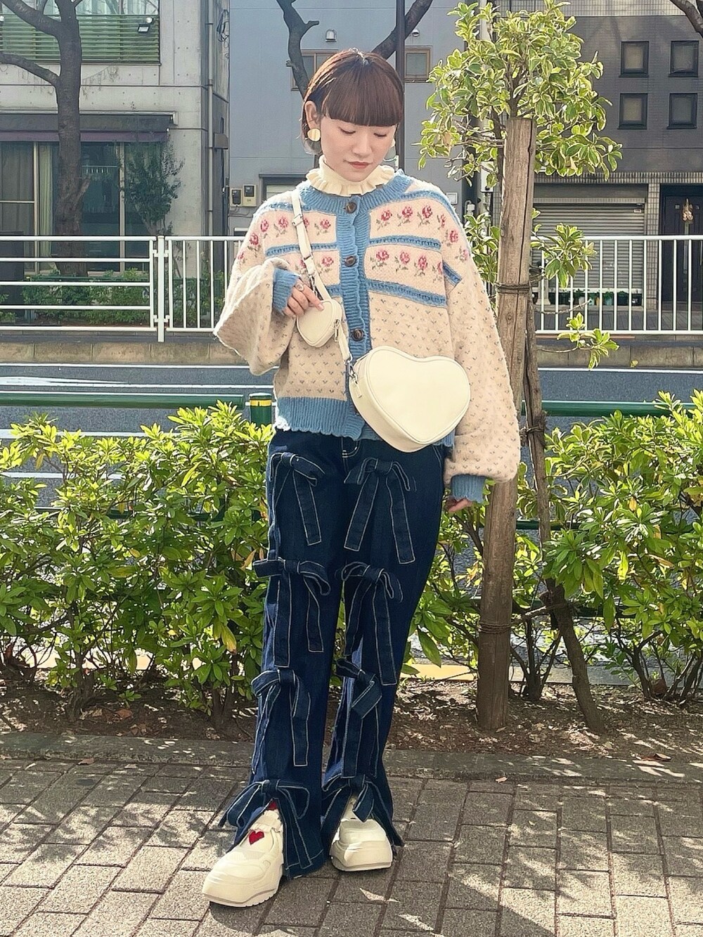 ホワイト系のハンドバッグ、ホワイト系のニット/セーター、ブルー系のカーディガン/ボレロを着用したレディースの冬コーディネートの2枚目の写真