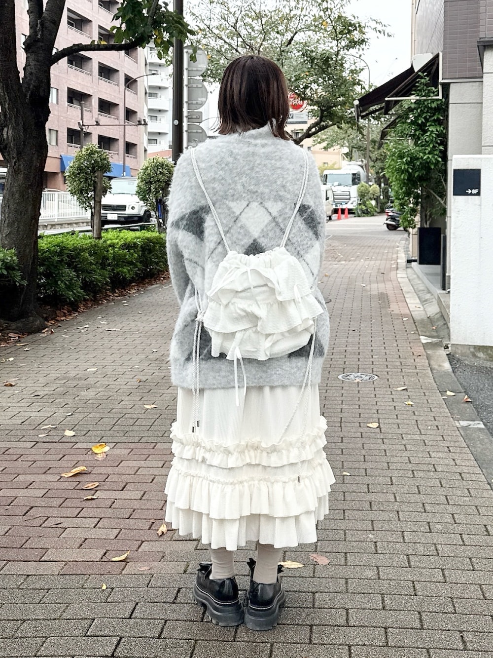 ホワイト系のスカート、グレー系のニット/セーター、ホワイト系のバックパック/リュックを着用したレディースの秋コーディネートの3枚目の写真