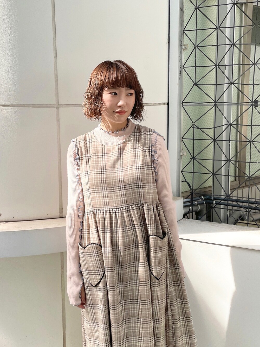 ピンク系のニット/セーター、ブラック系のデニムジャケット、ベージュ系のワンピースを着用したレディースの夏コーディネートの5枚目の写真