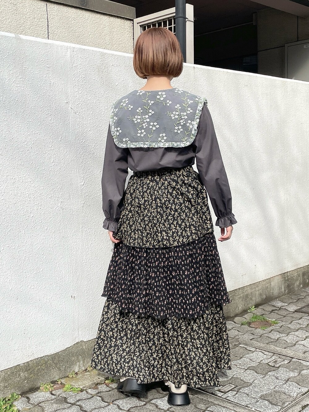 ピンク系のチェスターコート、ブラック系のスカート、グレー系のシャツ/ブラウスを着用したレディースの冬コーディネートの7枚目の写真