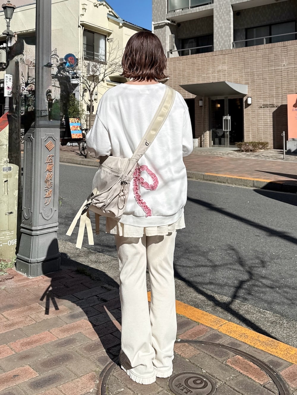 ホワイト系のスウェット、ベージュ系のメッセンジャーバッグ、ホワイト系のスウェットパンツを着用したレディースの冬コーディネートの2枚目の写真