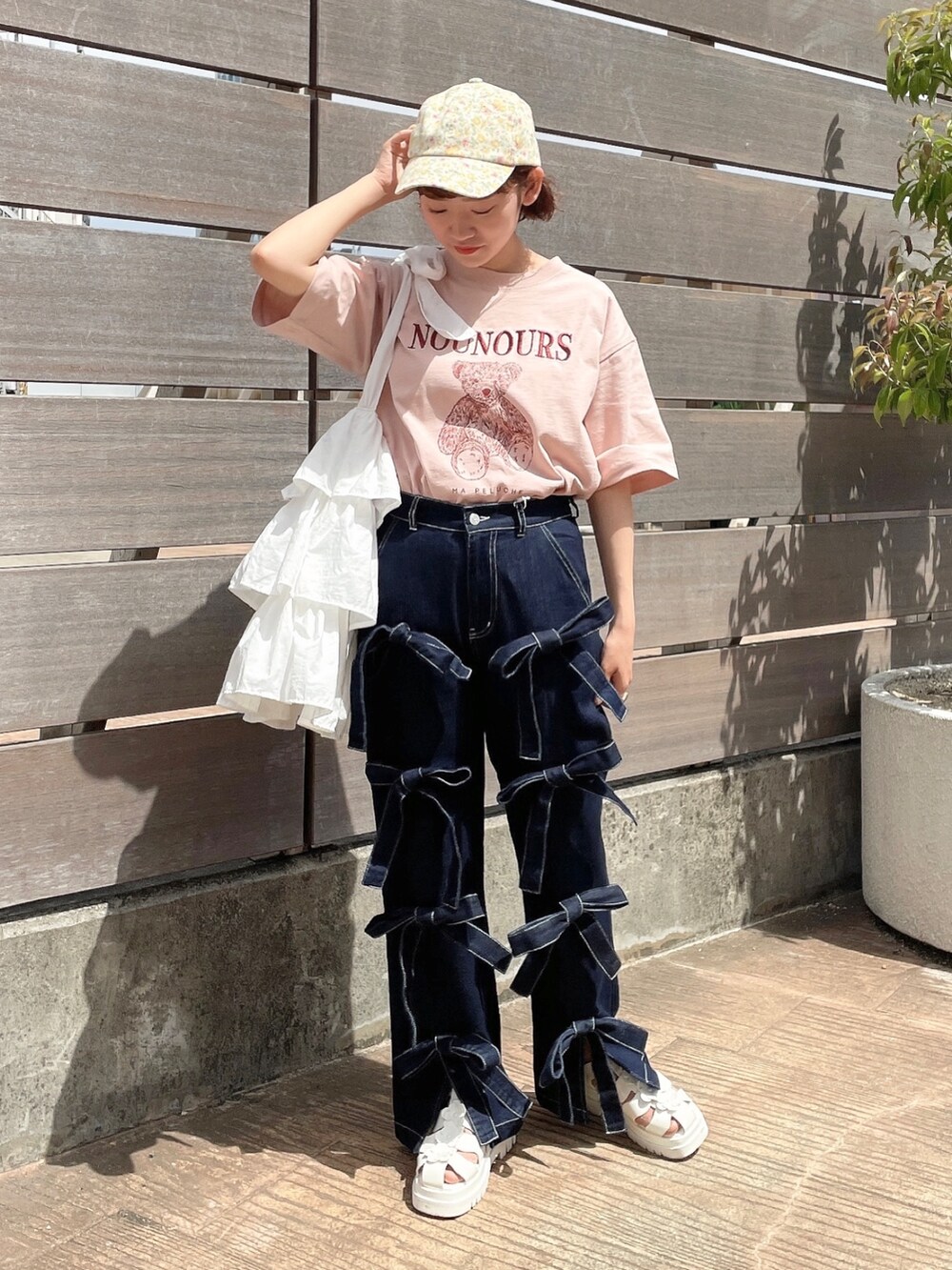 ピンク系のTシャツ/カットソー、ホワイト系のトートバッグ、ブルー系のデニムパンツを着用したレディースの春コーディネートの2枚目の写真