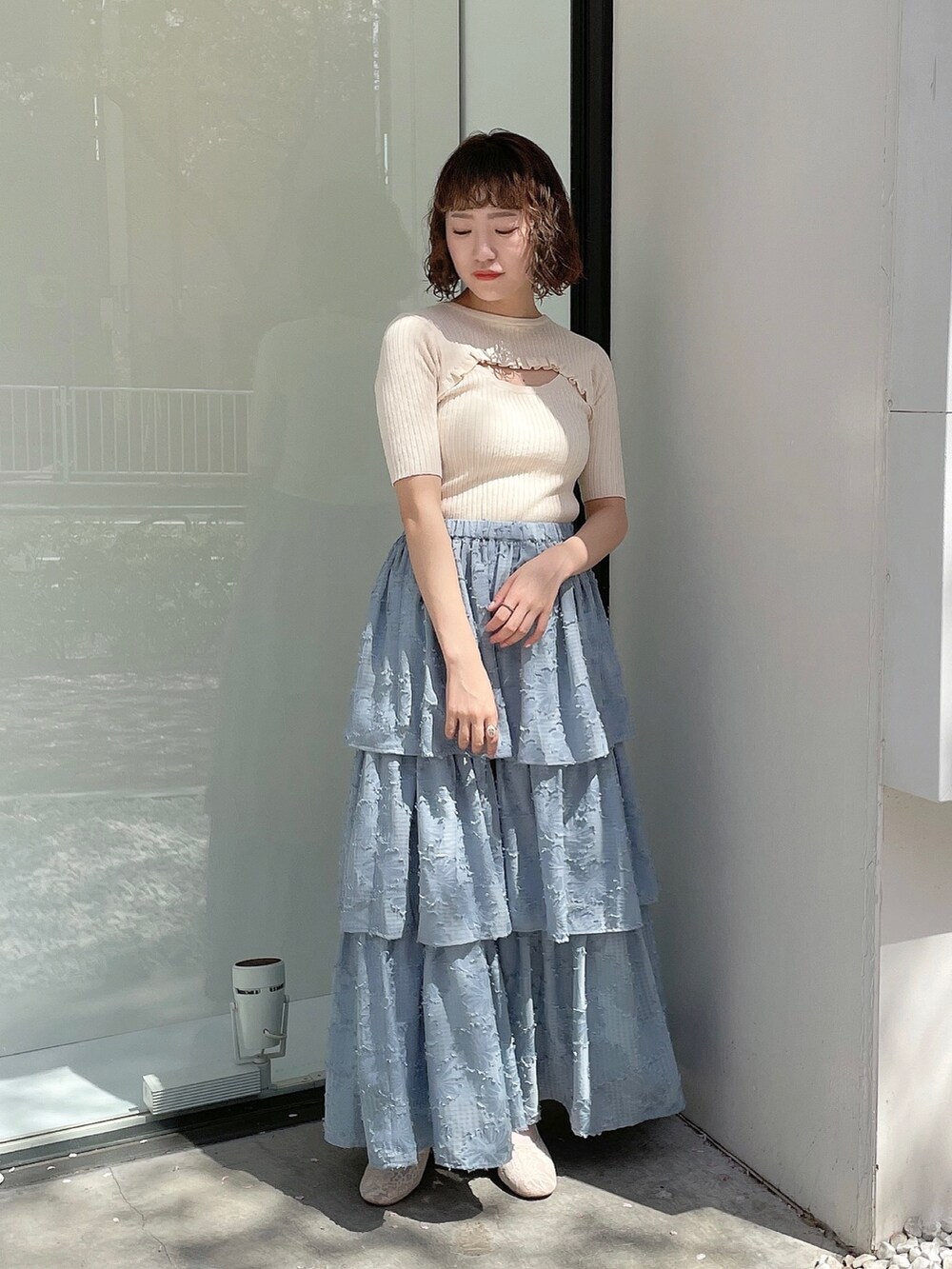 ブルー系のスカート、ホワイト系のニット/セーター、ホワイト系のパンプスを着用したレディースの春コーディネートの2枚目の写真